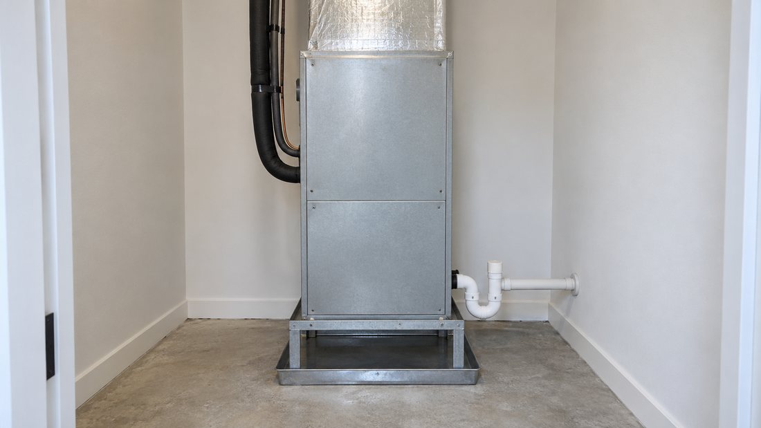 Closed indoor air handler with visible condensate plumbing